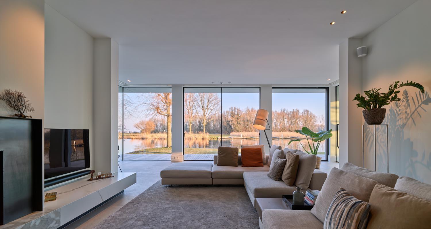 Moderne woonkamer met grote ramen en een open haard. 