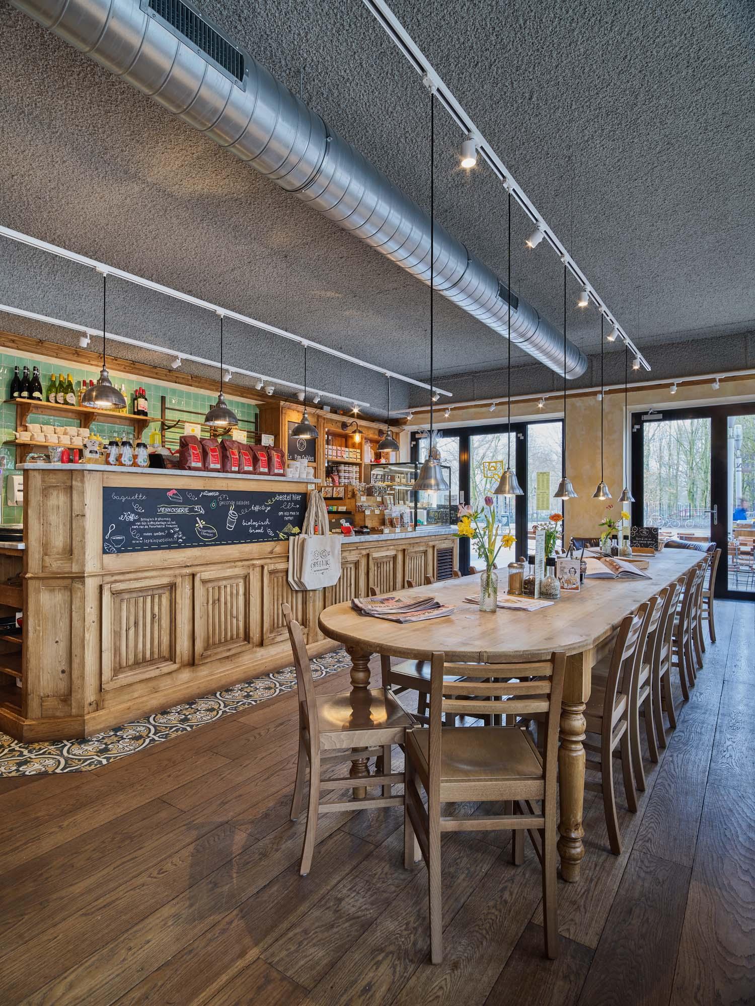 Houten tafels en stoelen in een gezellig restaurant met een grijs akoestisch, gespoten plafond.