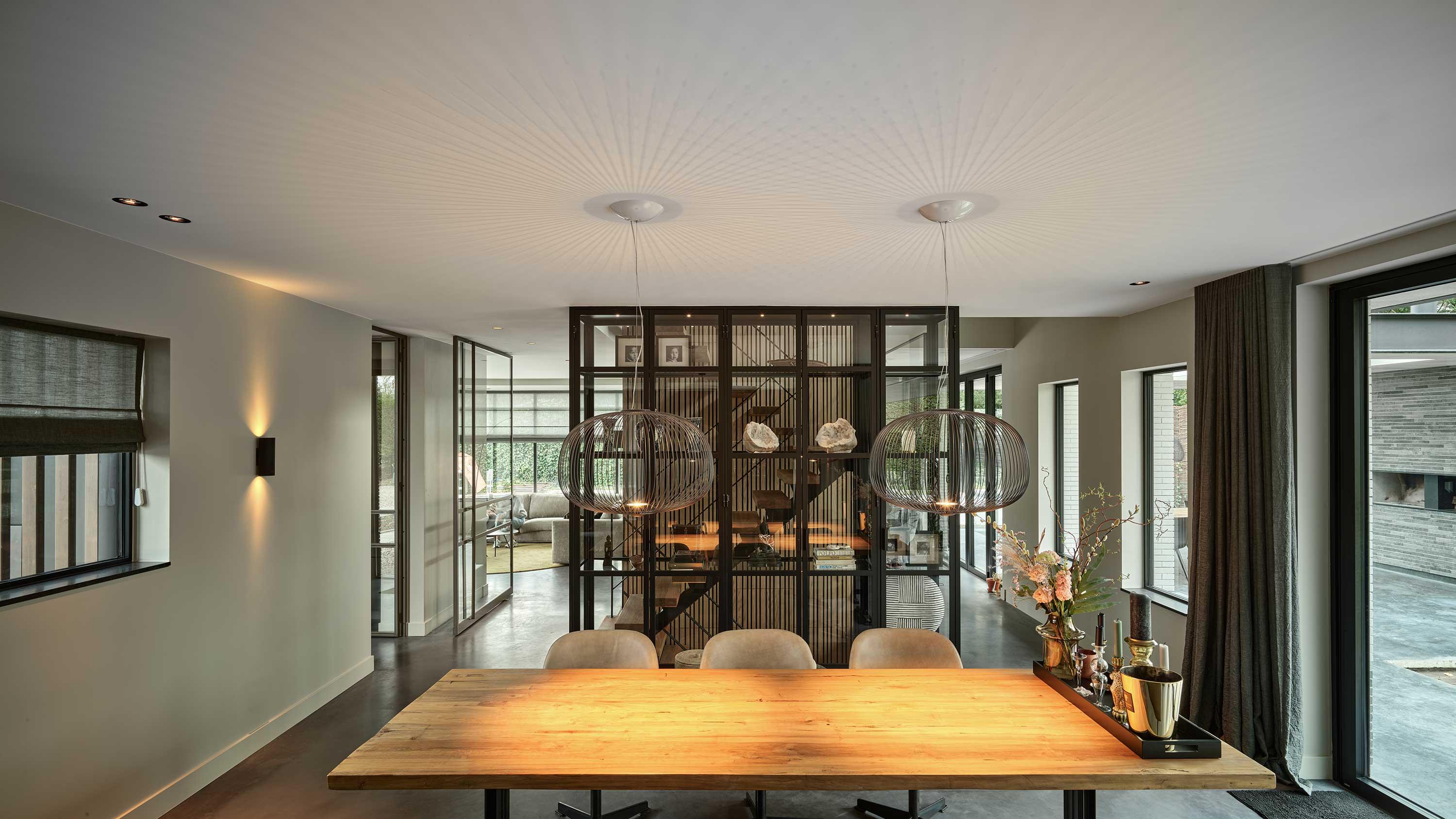 Een sfeervolle eetkamer met een tafel en stoelen en een naadloos akoestisch plafond.